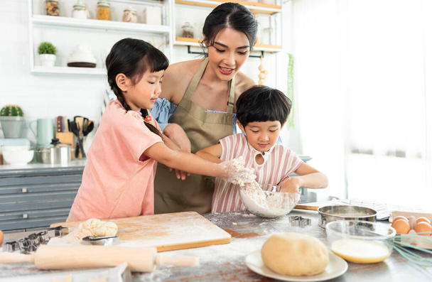 Glückliche asiatische Familie bereitet Teig zu und backt Plätzchen in der heimischen Küche. Gemeinsam die Familienaktivität genießen. - Foto, Bild