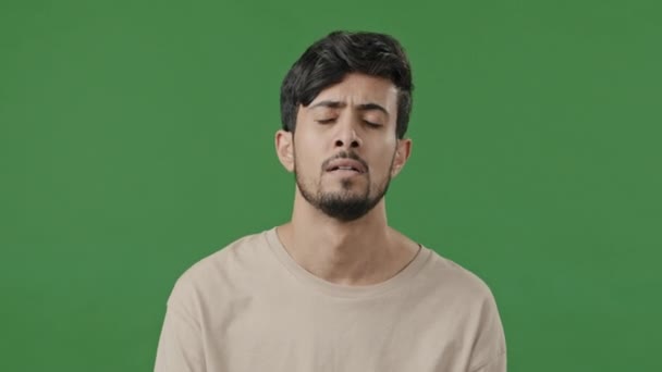 Arabian man upset disappointed young hispanic guy boyfriend in desperate standing on green background feeling stress frustration close male face with hand experiencing problem sadness emotion loosing - Záběry, video