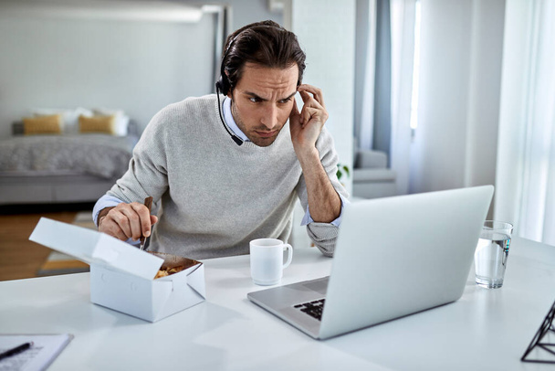 Молоді підприємці-чоловіки використовують комп'ютер під час обіду вдома
. - Фото, зображення