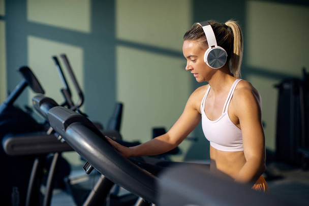 Athletic woman adjusting speed on running track while exercising in a gym.  - Photo, Image