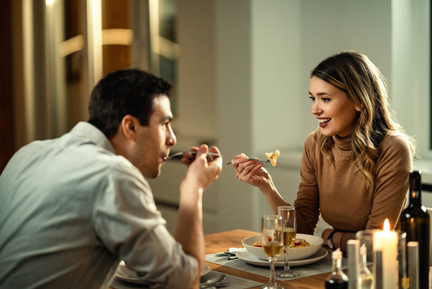 Young happy woman eating dinner and communicating with her boyfriend at dining table.  - Фото, зображення
