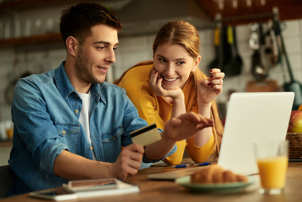 Happy couple using computer and shopping online with credit card at home. - Foto, Imagen