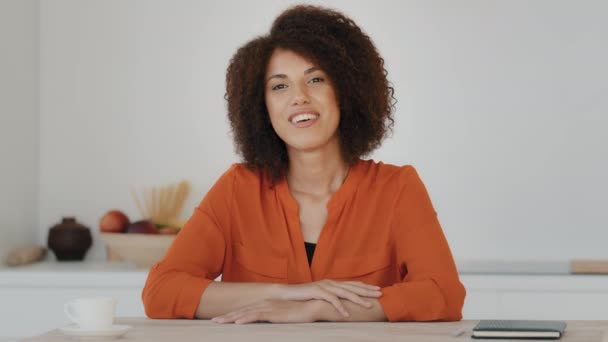 Webcam-Ansicht lächelnde Afroamerikanerin mit lockigem Haar sitzt zu Hause Küche Bloggerin weibliche Influencerin Vlogger winkende Hand hallo Gruß Gespräch in die Kamera hat Videotelefonie Konferenz-Chat - Filmmaterial, Video