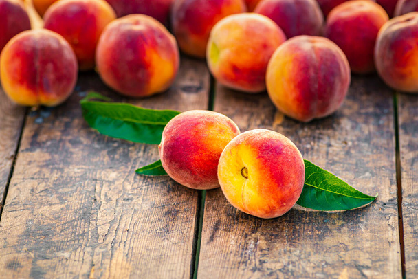 Group fresh peaches wood TABLE green natural background, (Prunus persica)  Harvest for food Delicious outdoors sunny day, Fresh ripe leaf, summer sunny garden juicy organic  sweet fruit, vegan food sunrise - Foto, imagen