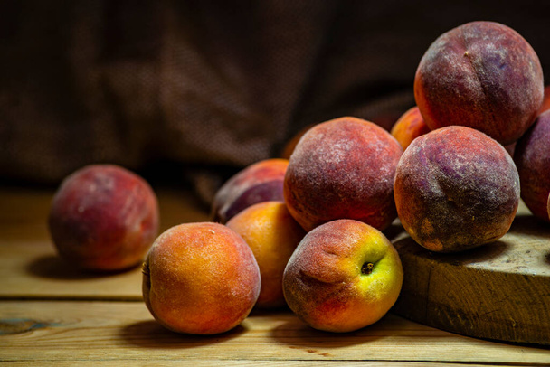 Group of fresh peaches on wood TABLE black background DARK MOOD,  ripe juicy organic  sweet fruit, vegan food, (Prunus persica) Close-Up, Harvest for food. - 写真・画像