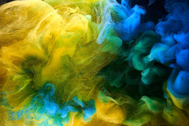 Liquid fluid art abstract background. Blue yellow dancing acrylic paints underwater, ocean space smoke - Foto, imagen