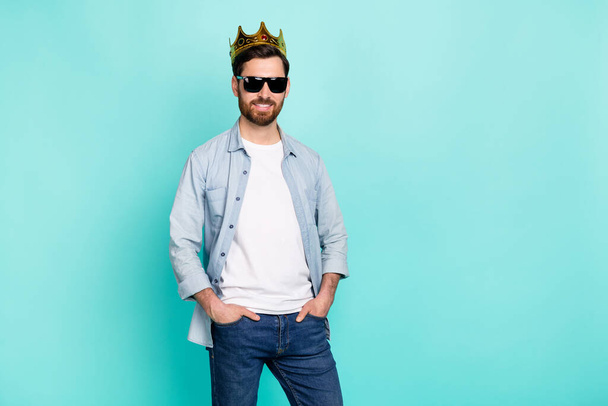 Portrait of positive cheerful man put hands pockets wear golden crown isolated on turquoise color background. - Foto, afbeelding
