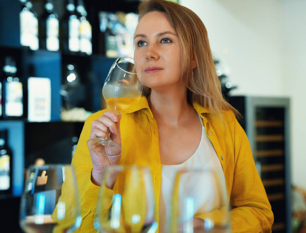 Vrouw is proeven witte wijn op een wijnmakerij. - Foto, afbeelding