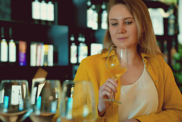 Женщина пробует белое вино на винодельне. - Фото, изображение