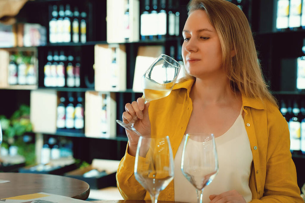Woman is tasting white wine at a winery. - 写真・画像