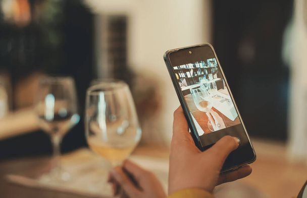 Woman takes a picture of glass of wine at tasting. - Foto, Bild