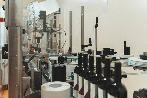 Automatische Linie zur Flaschenetikettierung in der Weinfabrik. - Foto, Bild