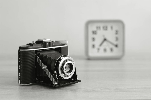 Vintage analoge Mittelformatkamera und eine Uhr in Schwarz-Weiß. Alte Filmkamera mit Blasebalg. - Foto, Bild