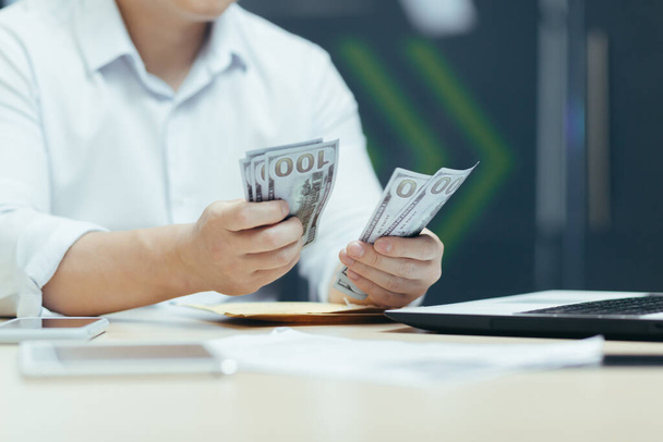 Foto de close-up das mãos de um homem de negócios em uma camisa contando dinheiro em dinheiro, um homem de negócios trabalha em um escritório moderno - Foto, Imagem
