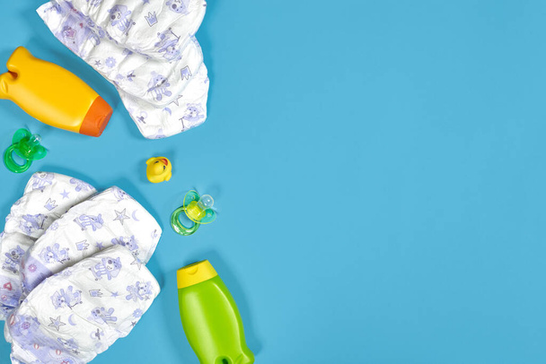 Baby care with bath set. Nipple, toy, diapers, shampoo on blue background top view mockup. Flat lay. Still life. Copy space - Fotografie, Obrázek
