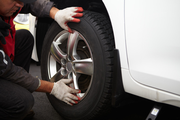Car mechanic changing tire. - Foto, Imagen