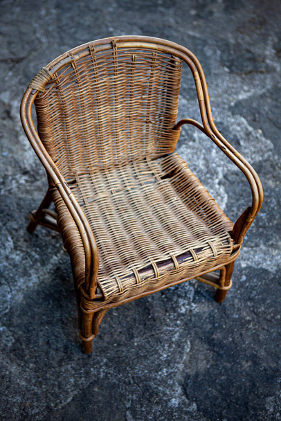 Old wicker chair on a stone floor - Fotoğraf, Görsel