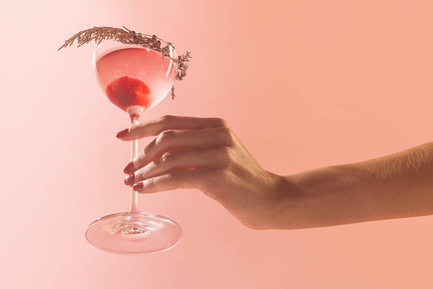 Glass of delicious alcohol drink with berries, cosmopolitan cocktail isolated over peach background. Concept of cocktails, alcoholic drinks, taste, party, mix. Copy space for ad. Retro style - Φωτογραφία, εικόνα