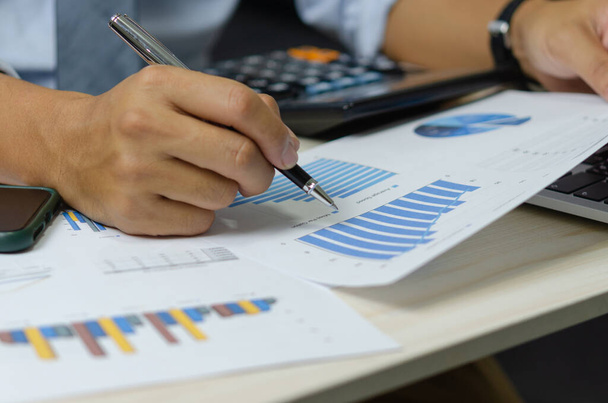 businessman holding pen to work computer graphs and charts data statistical data financial analysis documents. - Φωτογραφία, εικόνα