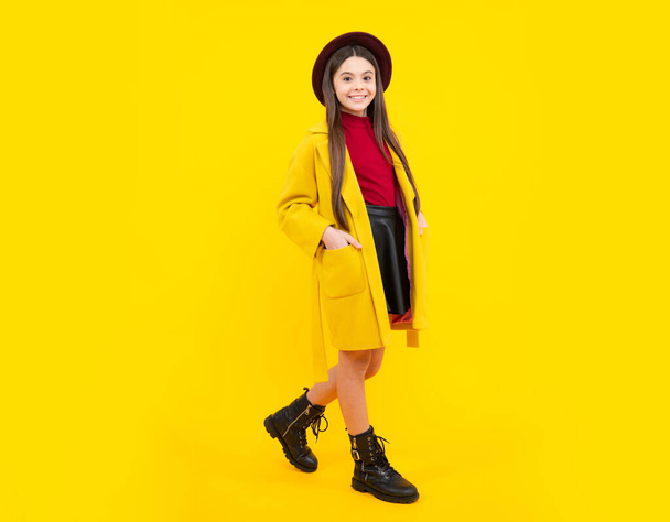 Full length of cheerful teenager child girl wearing comfy trendy fashion autumn coat, isolated over yellow background. Happy teenager portrait. Mock up copy space - Foto, Bild