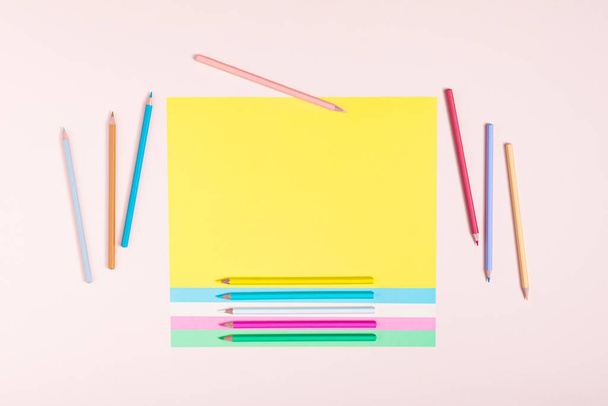 Pencils in pastel colors creatively arranged in a pattern on multicolored papers and a pink background. Back to school concept. Rectangular layout with copy space. Top view, flat lay. - Foto, imagen