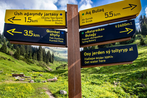 Signpost written in Kazakh, Russian and English of various hiking trails in Almaty mountains. Development of tourism in Kazakhstan. Almaty, Kazakhstan - June 06, 2022 - Foto, immagini