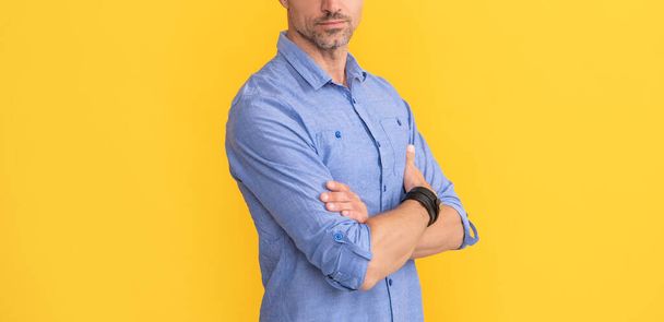 male fashion model on yellow background. handsome guy with graying bristle. mens beauty. hoary man portrait with crossed hands. cropped man with gray beard. hair and beard care. - Фото, изображение