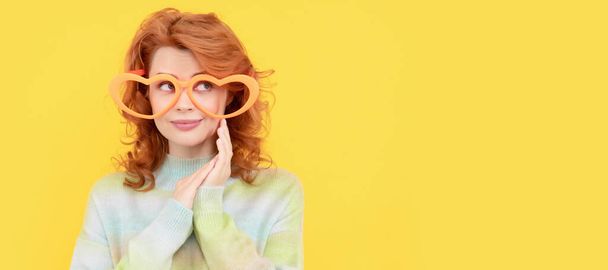 Woman isolated face portrait, banner with copy space. happy redhead woman wear funny party glasses on yellow background, party - Fotó, kép
