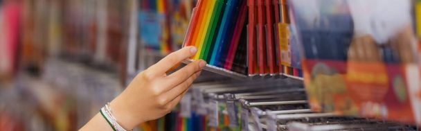 partial view of woman in beaded bracelets holding set of multicolored felt pens in blurred shop, banner - Foto, Imagen