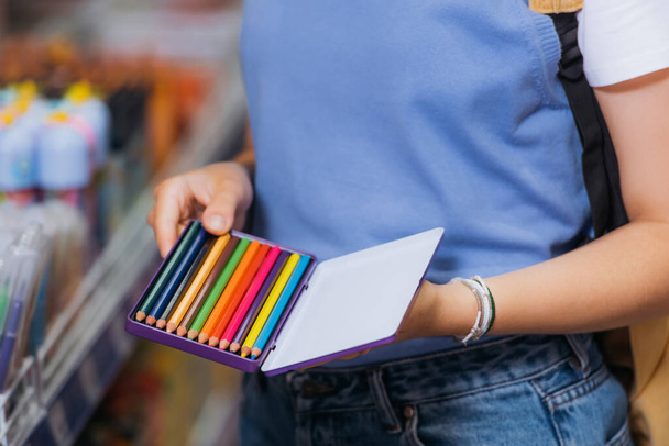 частковий вигляд жінки в браслетах з бісеру, що тримає набір кольорових олівців
  - Фото, зображення
