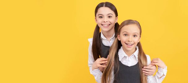 Шкільні дівчата друзі. Щасливі школярі з красою носять довге волосся у формальній формі жовтого фону. Портрет школярки, заголовок студійного банера. Шкільне дитяче обличчя, копія
 - Фото, зображення