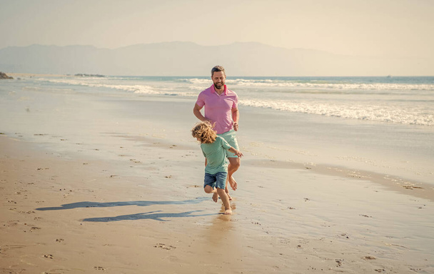 padre e hijo familia corriendo en la playa de verano, deporte familiar. - Foto, imagen