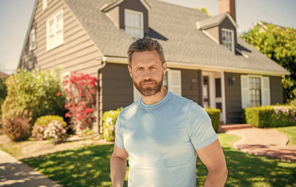 unshaven guy standing near new house, realtor. - Photo, Image
