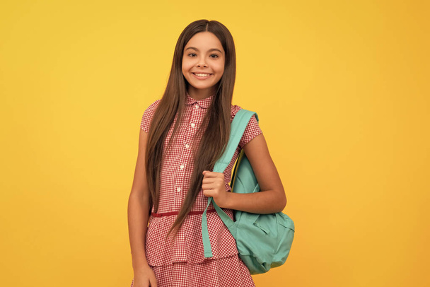 happy school child carry backpack on yellow background, school. - Zdjęcie, obraz