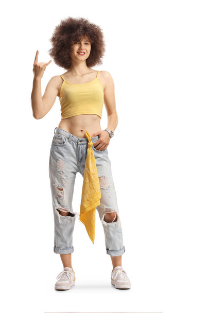 Full length portrait of a trendy young caucasian female with afro hairstyle gesturing a rock and roll sign isolated on white background - Photo, Image