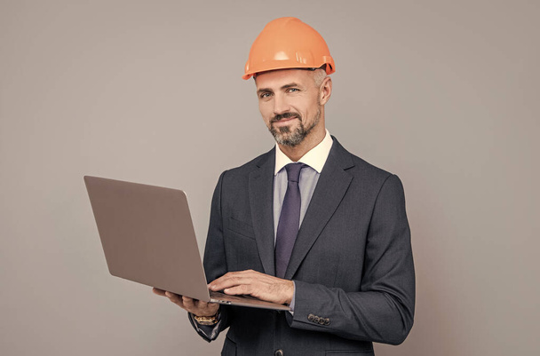 businessman man in building helmet texing message on laptop, business communication. - Фото, изображение