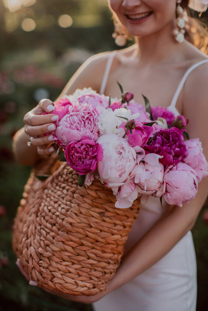 young woman with basket with pink peonies  - Fotoğraf, Görsel