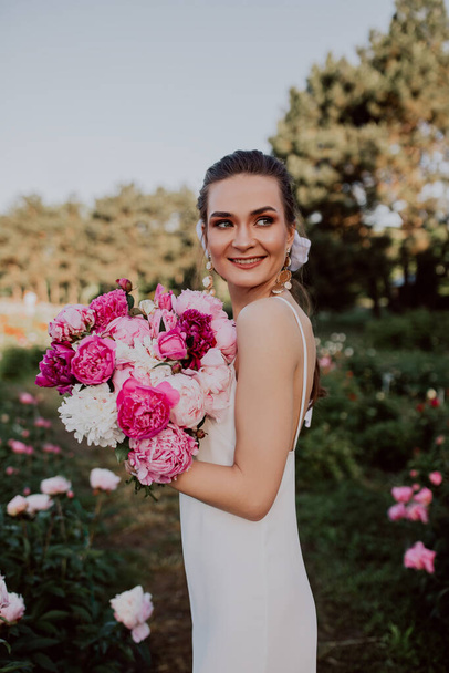 young woman with  pink peonies  - Foto, afbeelding
