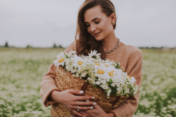 jonge vrouw met mand met bloemen in het veld  - Foto, afbeelding
