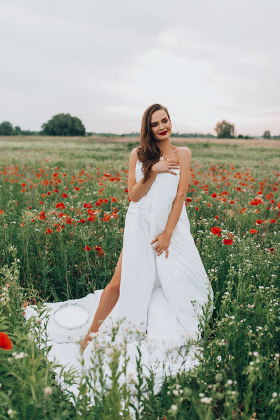 beautiful young  woman posing in blanket on the field of poppy flowers - Foto, imagen