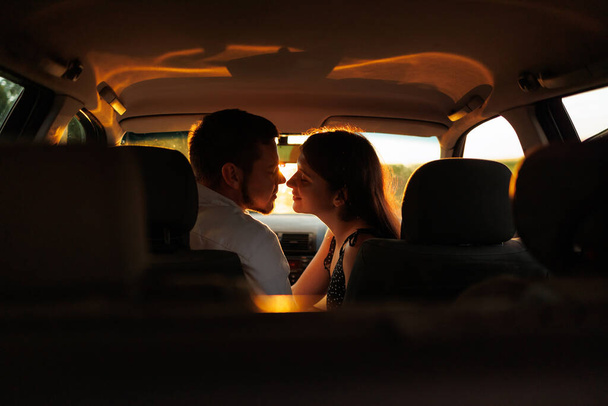 Pár szerelmes csók ül a kocsiban naplementekor - Fotó, kép
