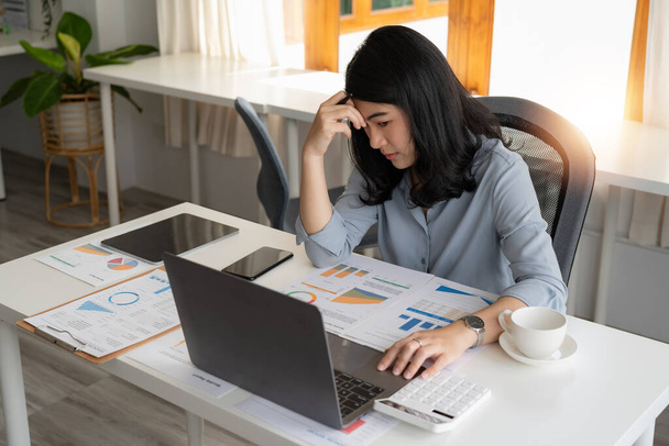 Jovem menina asiática trabalhando no escritório com laptop e calculadora pensando parecendo cansado e entediado com problemas de depressão. - Foto, Imagem