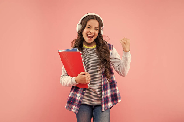 successful child listen music in headphones hold workbook on pink background, knowledge. - Fotografie, Obrázek