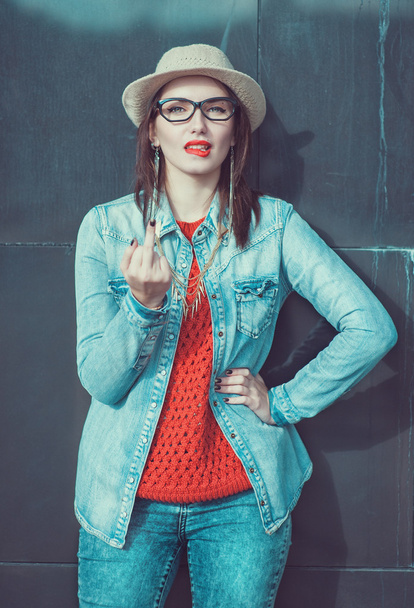 Young beautiful girl in red jersey and hat showing middle finger - Photo, Image