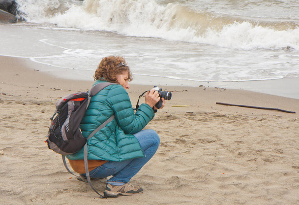Woman taking a picture near the shore of the Mediterranean Sea - Foto, Imagen