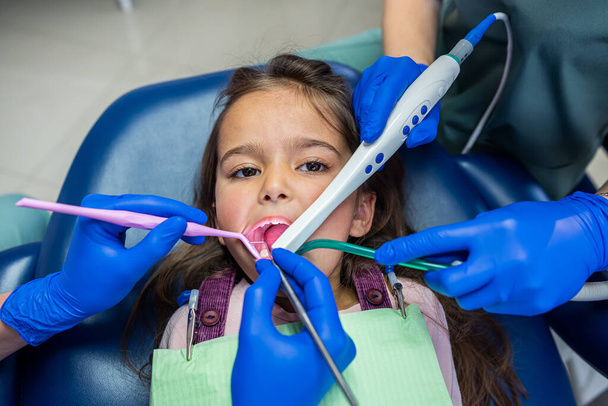 dentistas calificados revisan los dientes de los niños con nuevo equipo profesional. El concepto de examinar los dientes de los niños con una cámara - Foto, Imagen