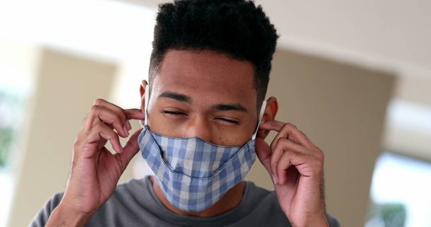 Young man removing covid-19 face mask feeling relief. Mixed race black ethnicity - Fotó, kép