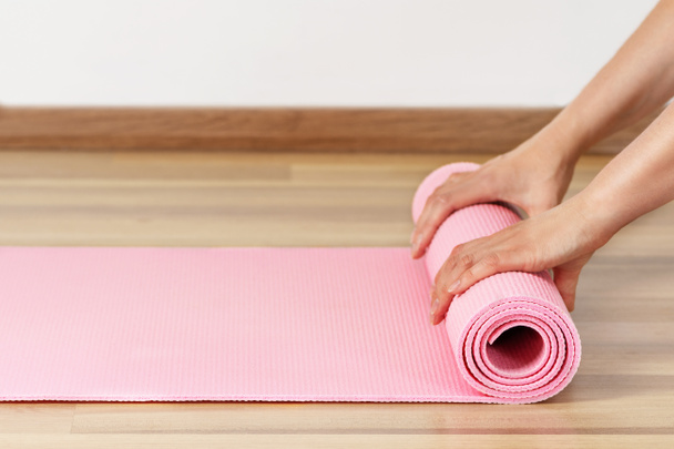 Woman rolling exercise mat in living room. Yoga or fitness workout at home. - Φωτογραφία, εικόνα