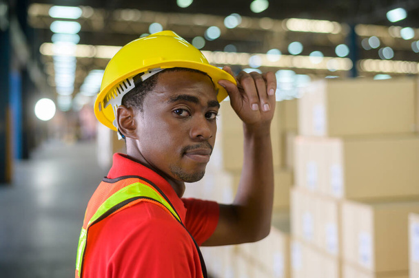 A Portrait of young mixed race male worker wearing helmet in modern warehouse storage of retail shop - Fotó, kép