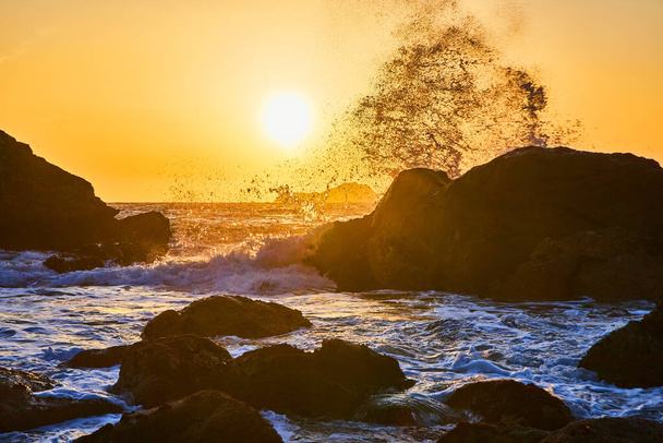 Image of Waves crash into boulders with vibrant sunset on west coast - Photo, Image